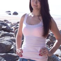 Petite brunette amateur Olivia showing off perky teen tits outdoors on rocky beach