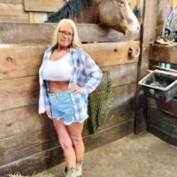 blonde amateur Maddie Cross exposes her huge tits while getting naked in a horse stall