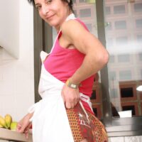 Mature dame strips in a kitchen before taking a banana to her hairy pussy
