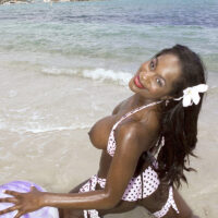 Ebony MILF Nikki Jaye releases her enhanced tits from her bikini top while on a beach