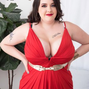 Tattooed BBW Nagini takes off a red dress while making her nude debut on a couch