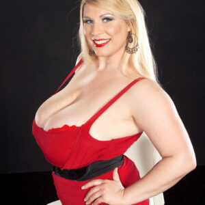Blonde BBW Renee Ross licks a nipple after releasing her huge breasts from a red dress