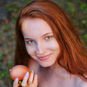 Beautiful girl with long red hair Lola Jolie goes nude in high heels near a fruit tree